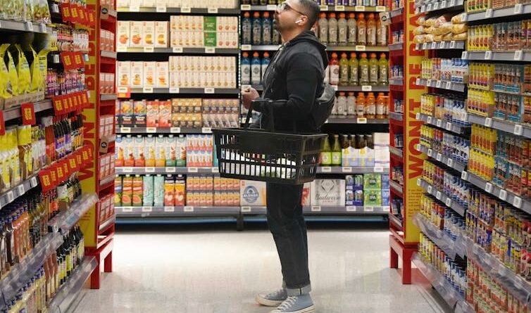 A man holding a basket of shopping in the way of grocery store