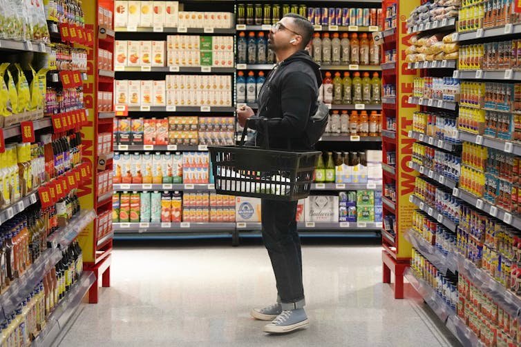 A man holding a basket of shopping in the way of grocery store